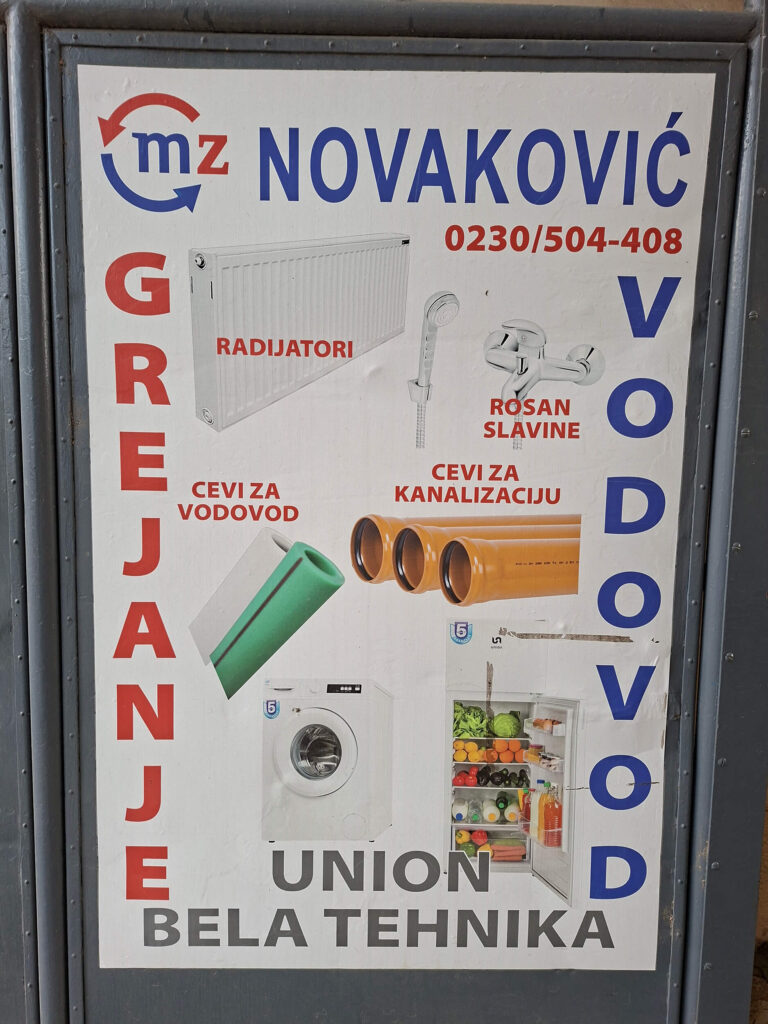 Reklamni pano prodavnice M.Z. Novaković u Kikindi sa ponudom za grejanje, vodovod, Rosan slavine i Union belu tehniku.